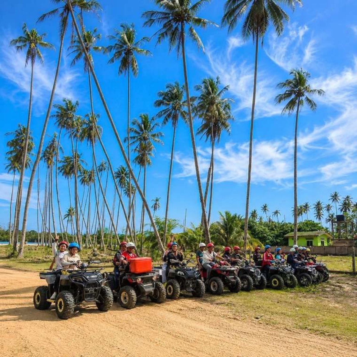 ATV riders lined up under coconut palms on the Setiu coast